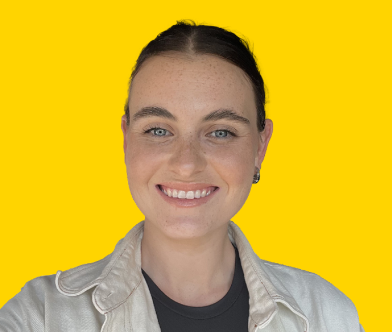 Bree Taylor - Headshot of a young woman with dark hair tied back, wearing a beige jacket and black t-shirt and smiling.