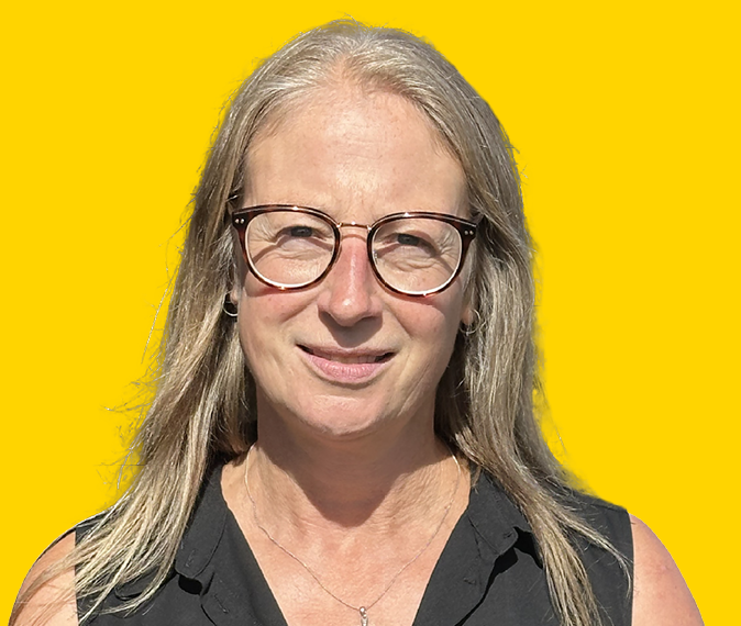 Caroline Brett – Headshot, wearing glasses looking at camera and smiling.