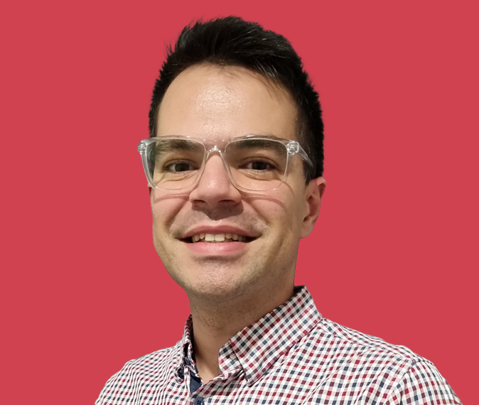 Jake Gneiding – headshot of a man with short, dark hair wearing a red, blue and white checked collared shirt, wearing glasses looking at camera and smiling. 